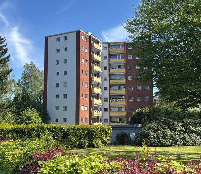 Achtgeschossiges Wohngebäude mit Balkonen hinter gepflegter Gartenanlage
